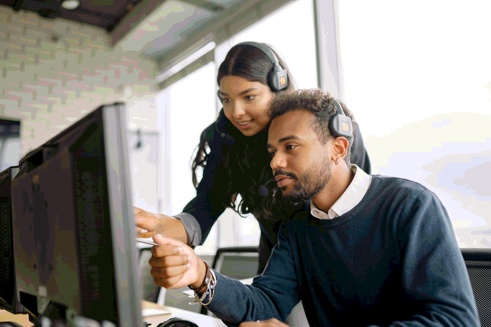 Support agents collaborating at a computer screen to resolve tickets