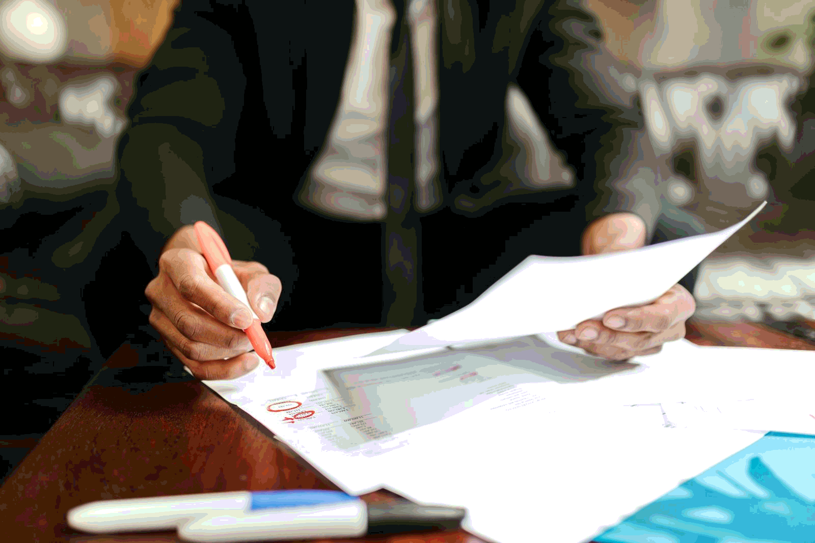 Business professional reviewing policy documents with a red marker at a desk