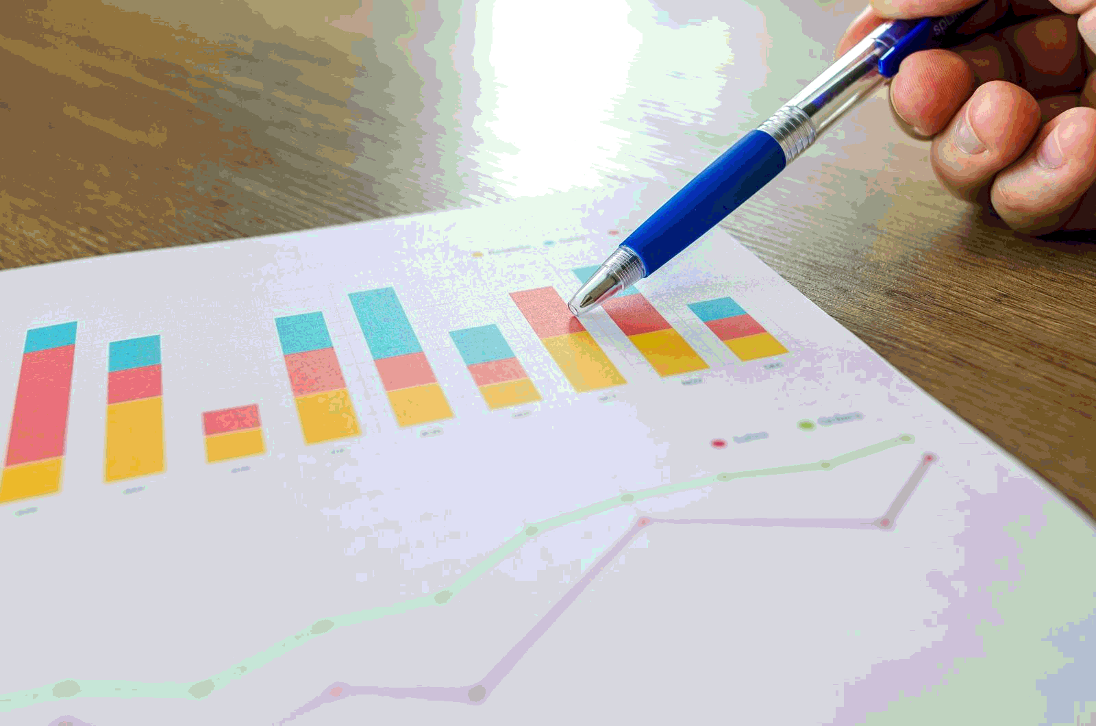 Person reviewing a printed financial graph with a pen during analysis